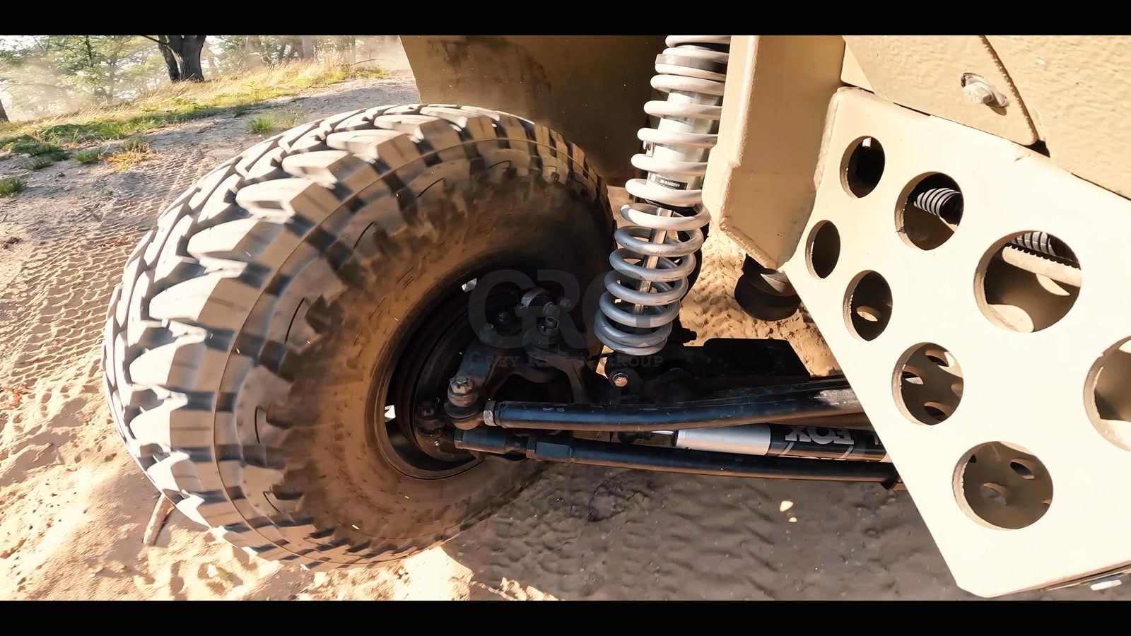 Close-up of vehicle suspension, coil spring, and off-road tire, GRG watermark visible